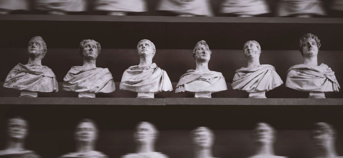 A black and white picture of rows of bust sculptures sitting on shelves