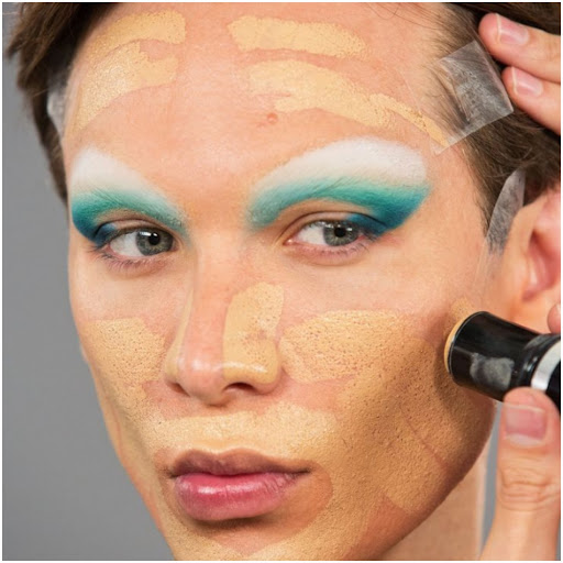 Miss Fame framing his face with foundation