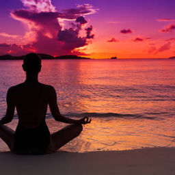 Woman meditating in front of a colorful sunset