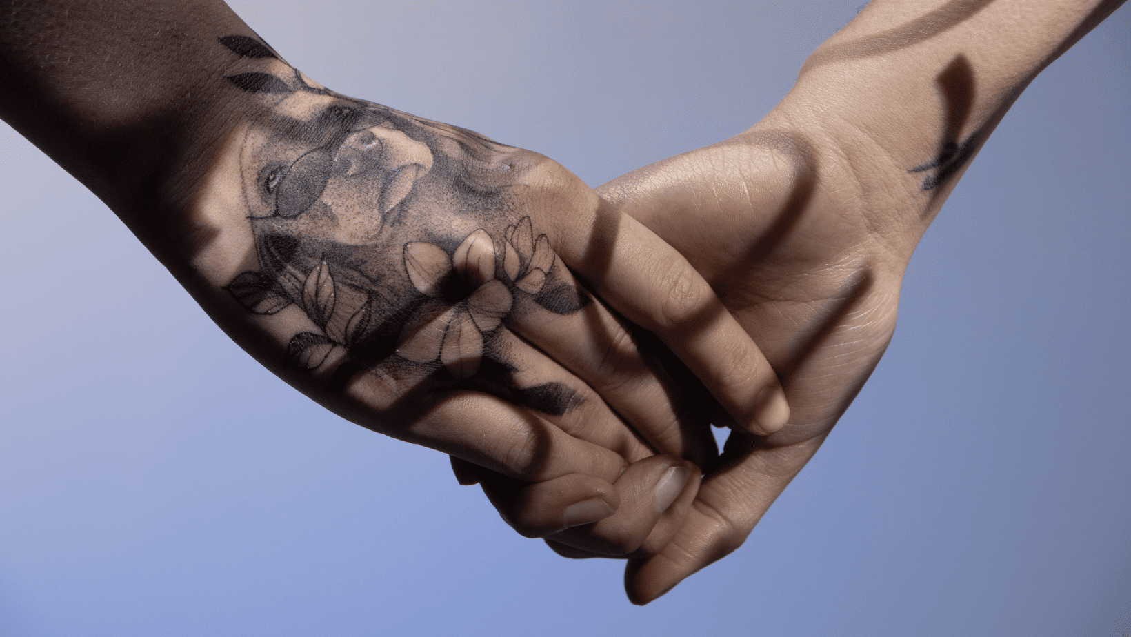 A tattooed hand holding another hand