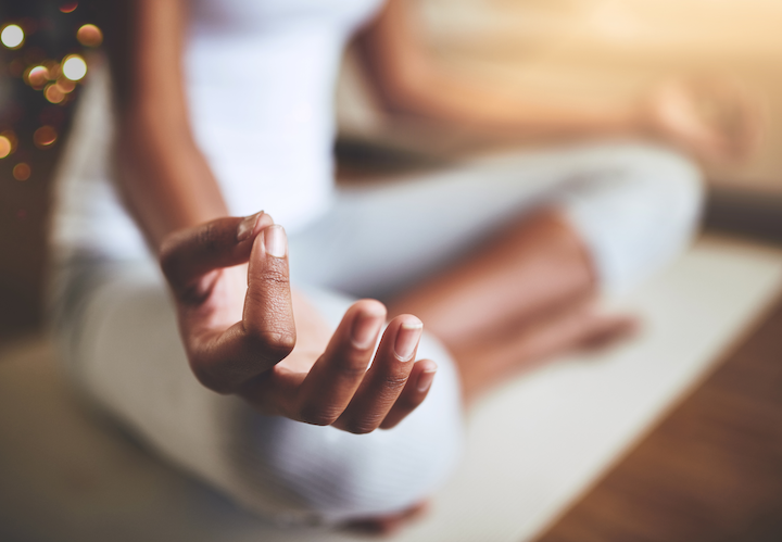 Corporate Wellness: A person in white yoga wear sitting in lotus pose with hands in a mudra