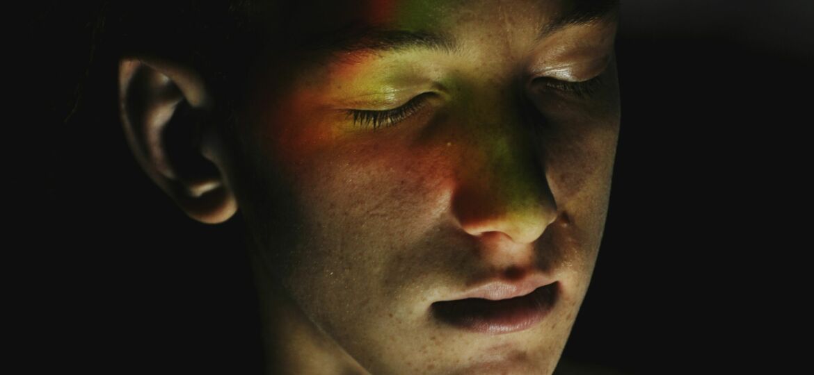 Man with eyes closed and prism light makeup over his face